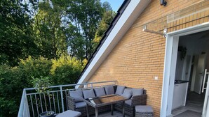 Una terraza con mobiliario exterior, un muro de ladrillo y una puerta de entrada.