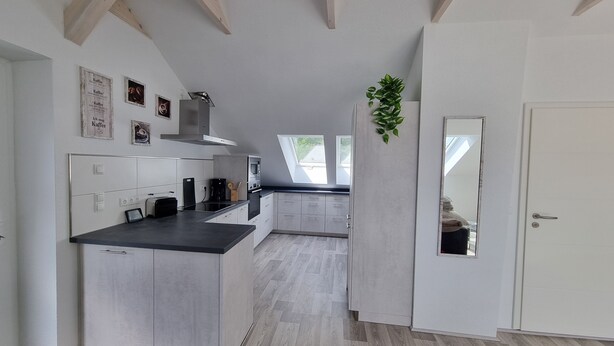 Una cocina moderna con una isla central, electrodomésticos integrados y vistas al comedor.