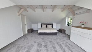 Un dormitorio con cama, mesitas de noche, cómoda y ventana con una planta.