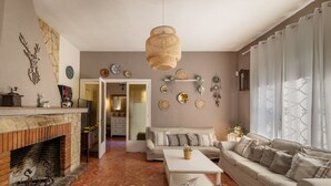 A living room with a fireplace, sofa, coffee table, and decorative wall art. - Holiday Home 'Tordera Village' with Mountain View, Private Pool and Wi-Fi (Tordera)