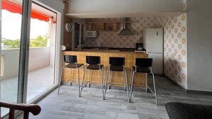 Une cuisine compacte comprenant un coin bar, un four à micro-ondes et un réfrigérateur.