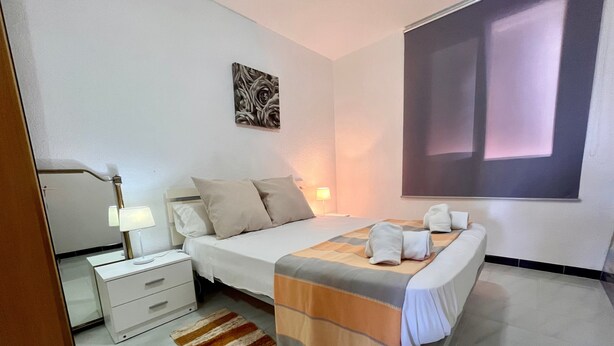 Une chambre à coucher avec un lit, des tables de chevet, une lampe, un tableau et une fenêtre.
