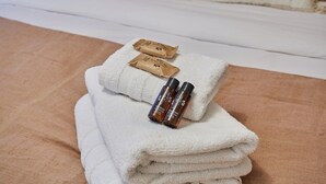 A neatly folded white towel with two small brown packages and two brown bottles on top.