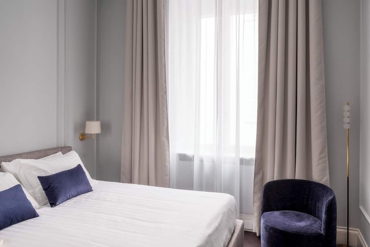 Ein Hotelzimmer mit einem Bett, einem Sessel und einem fenster mit Vorhängen.