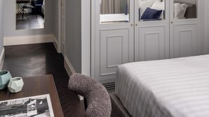 A bedroom with a large bed, a wardrobe with mirrors, a small table with a chair, and a mirror on the wall. - Golden House Vatican (Rome)