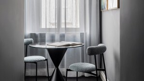 A modern dining area with a round table, four chairs, and a unique black conical base. - Golden House Vatican (Rome)