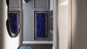 A hallway with a large mirror, two framed blue glass panels, and a blue bench. - Golden House Vatican (Rome)