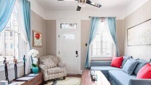 A living room with a sofa, armchair, coffee table, and a ceiling fan. - New Orleans Shotgun with private Patio (New Orleans)