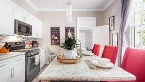 A modern kitchen with white cabinets, a stainless steel oven, and a central island with a plant. - New Orleans Shotgun with private Patio (New Orleans)