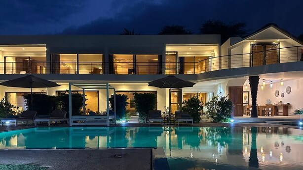 A modern two-story house with a swimming pool, outdoor seating, and well-lit windows. - Independent suite in luxury guest house (Ngaparou)