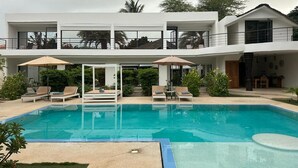 A modern two-story building with a swimming pool, outdoor seating, and a covered patio area. - Independent suite in luxury guest house (Ngaparou)