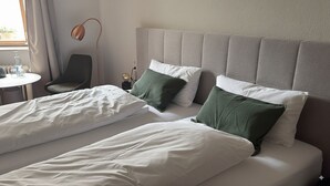 A hotel room with two beds, a chair, a table, and a lamp. - MYA Weinland Hotel Kobern-Gondorf (Kobern-Gondorf)