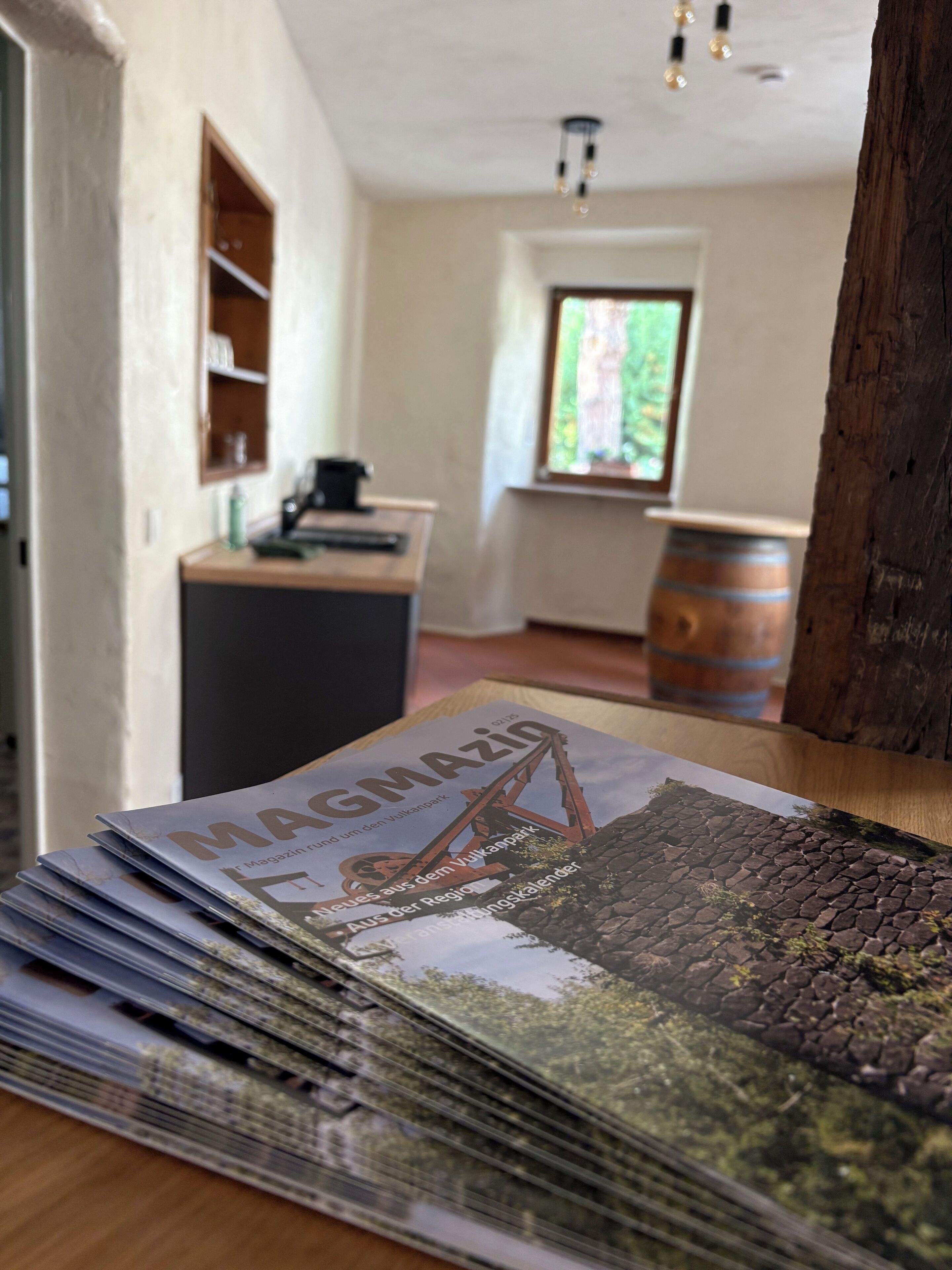 Zeitschriftenstapel auf einer Holztischplatte.