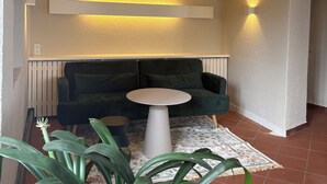 A modern living room with a green sofa, a white coffee table, and a large potted plant. - MYA Weinland Hotel Kobern-Gondorf (Kobern-Gondorf)