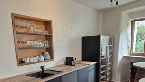 A modern kitchen with a wooden countertop, black cabinets, a built-in wine rack, and a coffee machine. - MYA Weinland Hotel Kobern-Gondorf (Kobern-Gondorf)
