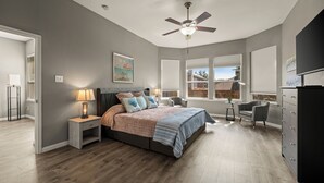 A bedroom with a bed, nightstands, a desk, a chair, a ceiling fan, and a large window. - Superb 4-bedroom house with AC in Fort Worth (Fort Worth)