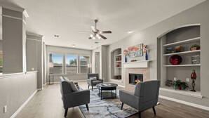 A spacious living room with a fireplace, grey sofas, and a ceiling fan. - Superb 4-bedroom house with AC in Fort Worth (Fort Worth)