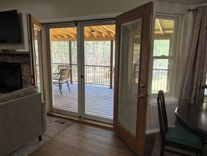 Una habitación con puerta de vidrio corredera que da a una terraza, chimenea, televisor y comedor con mesa y sillas.