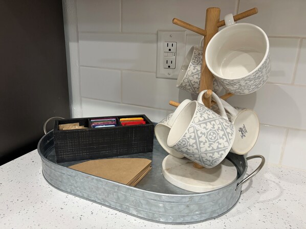 Una cocina con una bandeja metálica redonda que contiene tazas y un estuche negro para guardarla.