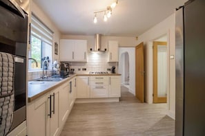 Une cuisine moderne avec des meubles blancs, un réfrigérateur en acier inoxydable et un îlot central doté d’une cuisinière.