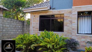 A modern house with a stone facade, a tiled roof, and a large window. - Residence Six Sigma (Entebbe)