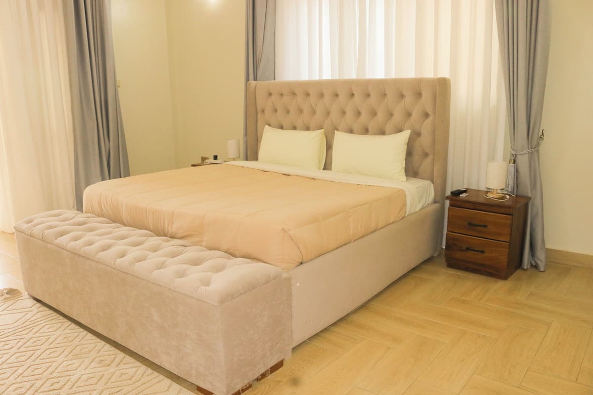 A bedroom with a large bed, a nightstand, and a wooden floor.