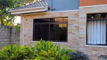 Une maison moderne avec une façade en pierre, un toit en tuiles et une grande fenêtre.