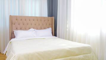 A neatly made bed with a tufted headboard, white linens, and a gold trim at the foot of the bed.