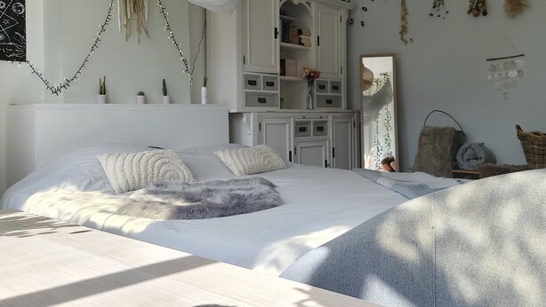 A bedroom with a large bed, a wardrobe, and a mirror. - Historic townhouse with 5 bedrooms In Holland's oldest city center, airco (Dordrecht)