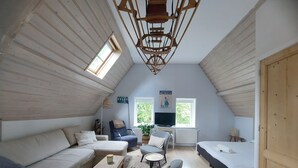 A cozy attic bedroom with a sloped ceiling, a sofa, a chair, a small table, and a bed. - Historic townhouse with 5 bedrooms In Holland's oldest city center, airco (Dordrecht)