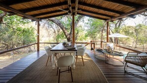 An outdoor covered dining area with a wooden table and chairs, surrounded by natural scenery. - Karongwe - Noka House (Hoedspruit)