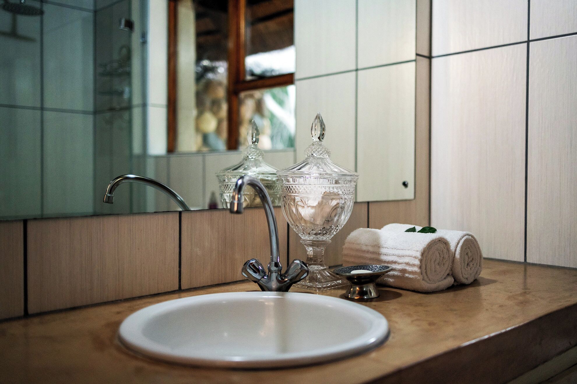 Un baño con un lavabo blanco, un tarro de vidrio y una toalla en la encimera.