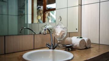 Un baño con un lavabo blanco, un tarro de vidrio y una toalla en la encimera.