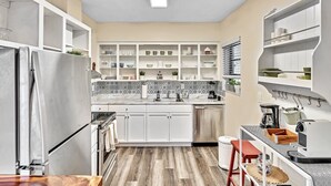 Een moderne keuken met witte kasten, een betegelde spatwand en een inbouwkastenwand.
