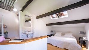 Un dormitorio con cama, mesita de noche, ventana y baño con lavamanos y espejo.