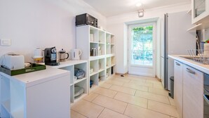 Una cocina moderna con armarios blancos, una cafetera y un mueble de estanterías empotrado.