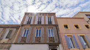 A building with multiple windows and balconies, featuring a classic architectural style with shutters and decorative ironwork. - Monte Bello - Charmant Appt 2 personnes (Marseille)