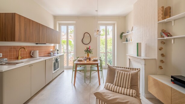 A modern kitchen with a dining area, wooden cabinets, and a view of the outdoors through large windows. - Monte Bello - Charmant Appt 2 personnes (Marseille)