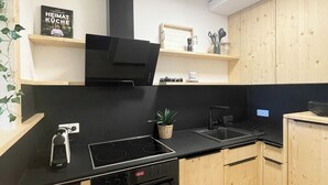 Een moderne keuken met zwarte apparaten, houten keukenkastjes en een kleine potplant.