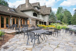 A stone-paved patio with outdoor seating and a building with a stone facade and multiple windows.