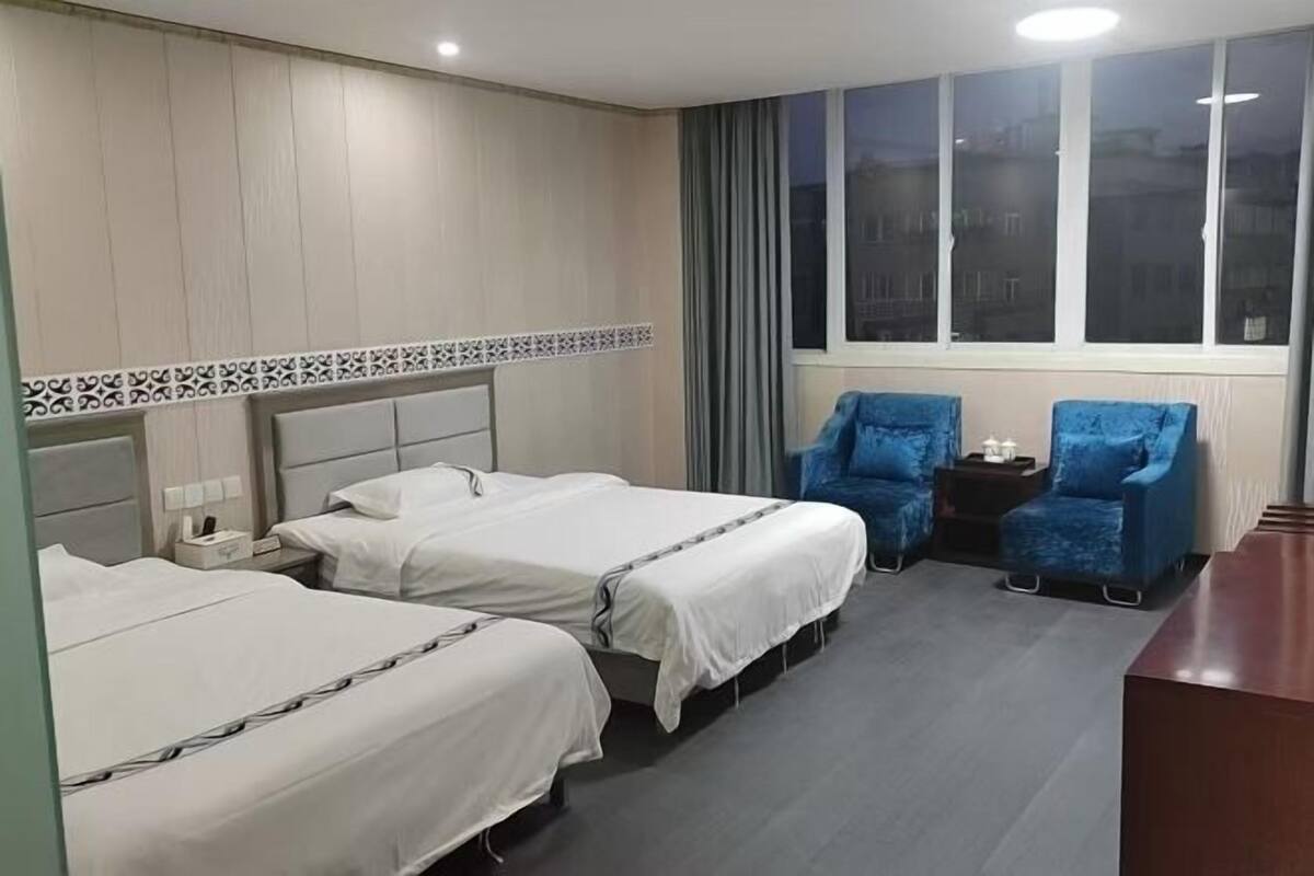 A hotel room with two beds, a desk, and a chair.