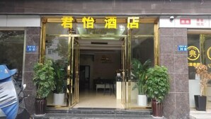 A hotel entrance with a glass door, potted plants, and a sign above the door.