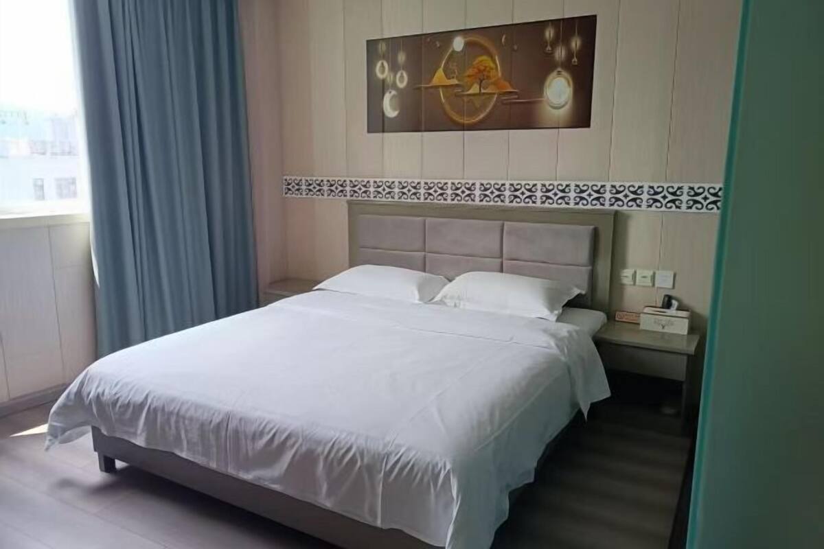 A neatly made bed with white linens in a hotel room.