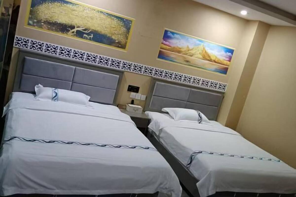 A hotel room with two beds, a nightstand, and wall-mounted artwork.