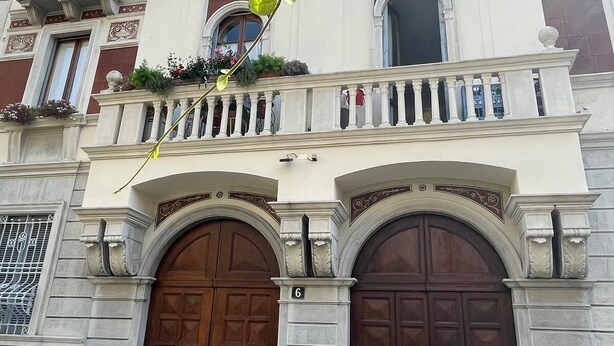 Een historisch gebouw met twee grote houten deuren, een balkon met leuningen en decoratieve ornamenten.