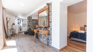 Une chambre moderne avec un grand lit, une commode en bois et un mur d’accent en pierre.