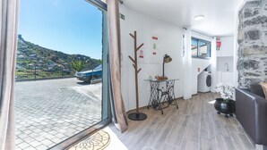 Une chambre d’hôtel moderne dotée d’une grande fenêtre, d’un mur décoratif en pierre, d’un canapé, d’une petite table avec une lampe et d’un lave-linge.