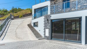 Un bâtiment moderne avec une façade en pierre, de grandes fenêtres et un escalier menant à un deuxième étage.