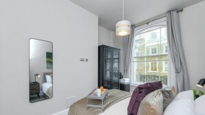 Habitación de hotel moderna con una cama grande, una mesita de noche con una bandeja de desayuno, un armario y una ventana con cortinas.