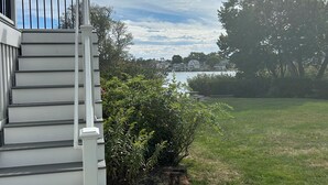A staircase leading to a deck with a view of a lake and trees. - Serene Waterfront 3-BR house with Loft, 1 mile walk to Charlestown beach (Charlestown)